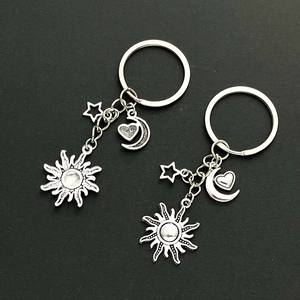 Detailed view of two silver alloy keychains with sun, moon, and star pendants on black background