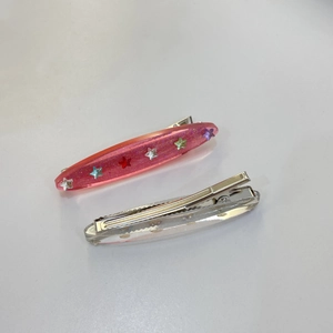 Detail of pink and clear glittery star hair clips with duckbill metal grips for women
