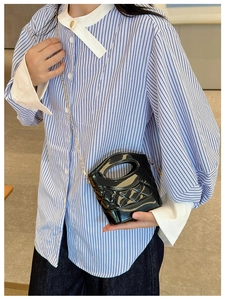 Dettaglio di una mini borsa a secchiello trapuntata nera con catena indossata da una modella