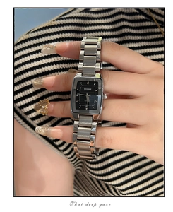 Close-up of rectangular silver steel watch with black dial and calendar display
