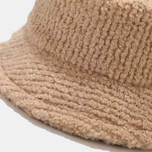 Detailed macro view of plush lamb wool fabric texture on a beige winter bucket hat