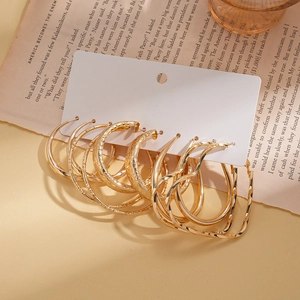 Detailed view of six pairs of gold hoop earrings in round, twisted, and heart-shaped designs