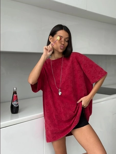 Détail d'un t-shirt rouge oversize avec motifs de cœurs en relief et épaules tombantes