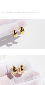 Detail shot of polished gold water drop earrings with a reflective metallic finish