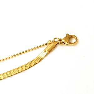 Detail view of double-layer gold snake chain anklet with lobster clasp and bead chain