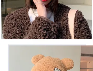 Close-up of plush bear ear hat featuring a detailed embroidered text label on the side