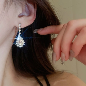 Close-up of silver water drop tassel earrings with sparkling rhinestones on model