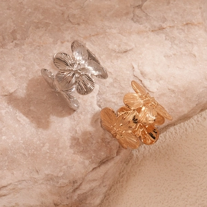 Macro detail of gold and silver metal flower rings on natural stone background