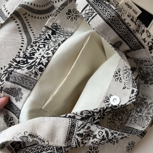 Detail of paisley print bag featuring magnetic silver buckle and internal pocket