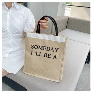 Detail of eco-friendly linen tote bag with black woven handles and printed typography