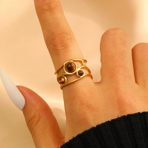 Detailed view of a gold open ring with tiger eye stones worn on a finger
