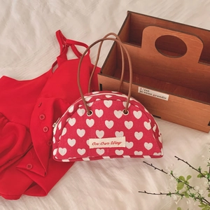 Detail of red semicircular canvas bag with white heart patterns and brown handles