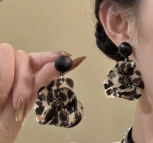 Detail of leopard print resin flower earrings with gold rose core and black studs