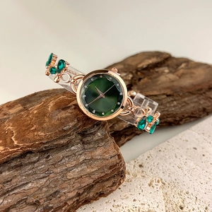 Detailed shot of emerald green crystal bracelet watch with rose gold case on wood
