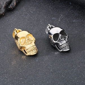Polished gold and silver skull pendants on dark stone background for men