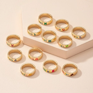 Detailed close-up of 12 zodiac gold rings with colored symbols on pink stone surface
