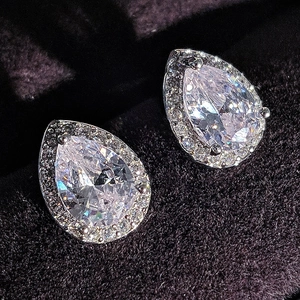 Macro detail of pear-shaped halo earrings with sparkling cubic zirconia on dark velvet