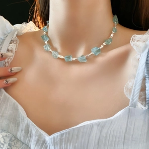 Dettaglio della collana con pietre azzurre e perline argentate sul collo della modella