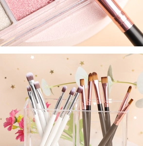 Detail of professional eye makeup brushes in acrylic holder with shimmery eyeshadow palette