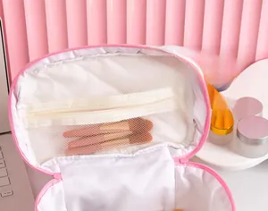 Detail view of pink cosmetic bag with interior mesh pocket holding makeup brushes