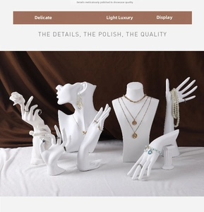 Detailed view of white resin bust and hand models displaying necklaces and rings on velvet