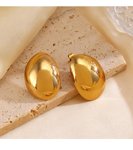 Detailed macro shot of oval gold-plated earrings on marble with yellow silk background