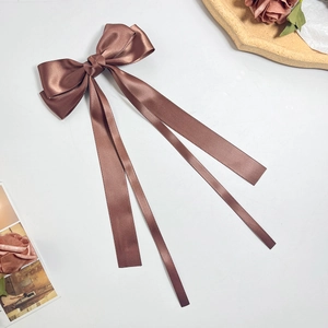 Detail of elegant brown satin ribbon bow hair clip with flowing long streamers