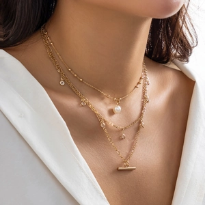 Detail of layered gold necklace with white pearls and sparkling crystal pendants