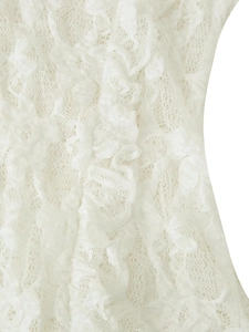 Macro shot of white lace knitted top detail showing intricate floral patterns and ruffles