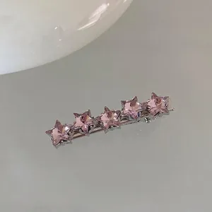 Detail of silver hair clip with five shimmering pink rhinestone stars in a row