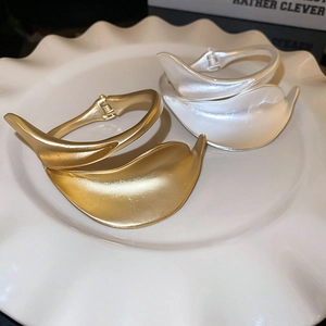 Detailed shot of matte gold and silver organic leaf-shaped cuffs on a decorative plate