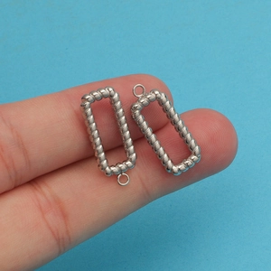 Close-up of twisted silver-colored rectangular titanium steel pendants for DIY jewelry
