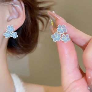 Détail des boucles d'oreilles fleurs en résine bleu clair avec bordure dorée élégante