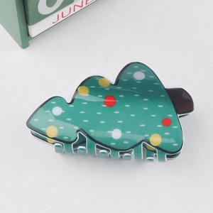 Détail de la pince à cheveux sapin de Noël verte avec pois colorés sur fond blanc