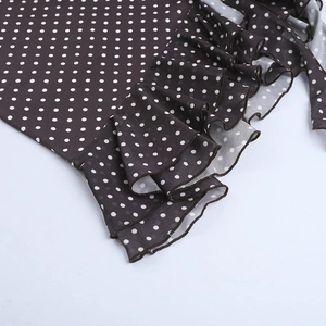 Détail du tissu marron à pois blancs avec bordure à volants sur la robe élégante