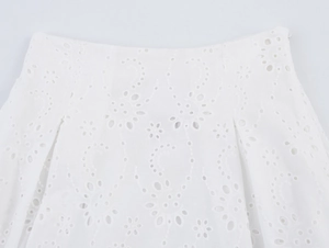Κοντινό πλάνο με λευκά κεντήματα eyelet και γεωμετρικά διάτρητα σχέδια στο βαμβακερό φόρεμα