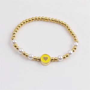 Minimalist gold plated beaded bracelet featuring white pearls and a yellow heart charm