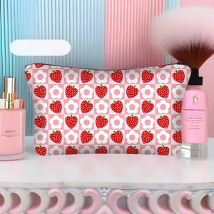 Close-up of strawberry and flower print on pink checkered polyester makeup bag with zipper