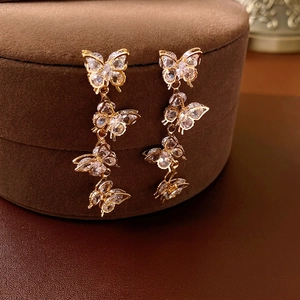 Elegant gold butterfly tassel earrings with sparkling zircon crystals on dark velvet