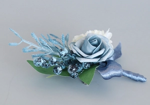 Detail of dusty blue foam rose boutonniere with frosted berries and greenery for weddings