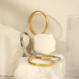 Polished 18k gold and silver diamond-pattern stainless steel bangles on stones