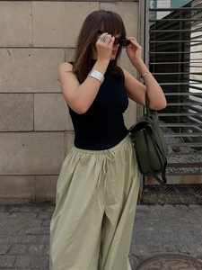 Detail of light green cotton wide-leg pants with drawstring waist and black tank top
