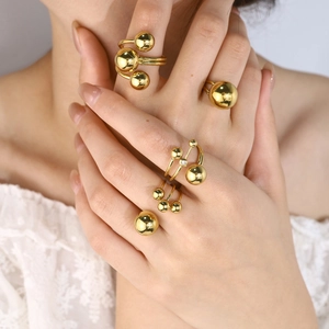 Polished gold stainless steel ball rings set on hand with elegant lace background