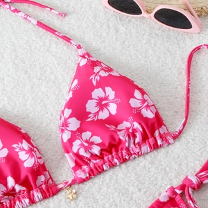 Detailed macro of pink bikini top with white floral print and a gold flower pendant