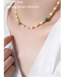 Dettaglio della collana con perle d'acqua dolce, sfere dorate e pietre preziose verdi
