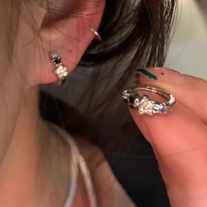 Macro detail of silver star hoop earring with black and white zircon stone pavé