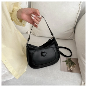 Detail of black handbag with 3D heart design and dual straps for versatile carrying