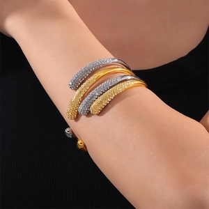 Bracelet spirale ouvert doré et argenté avec strass brillants sur le bras du modèle