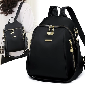Detail of black nylon backpack with golden metal zippers and textured logo straps