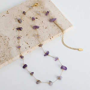 Handmade gold stainless steel necklace with purple natural stones on travertine stone
